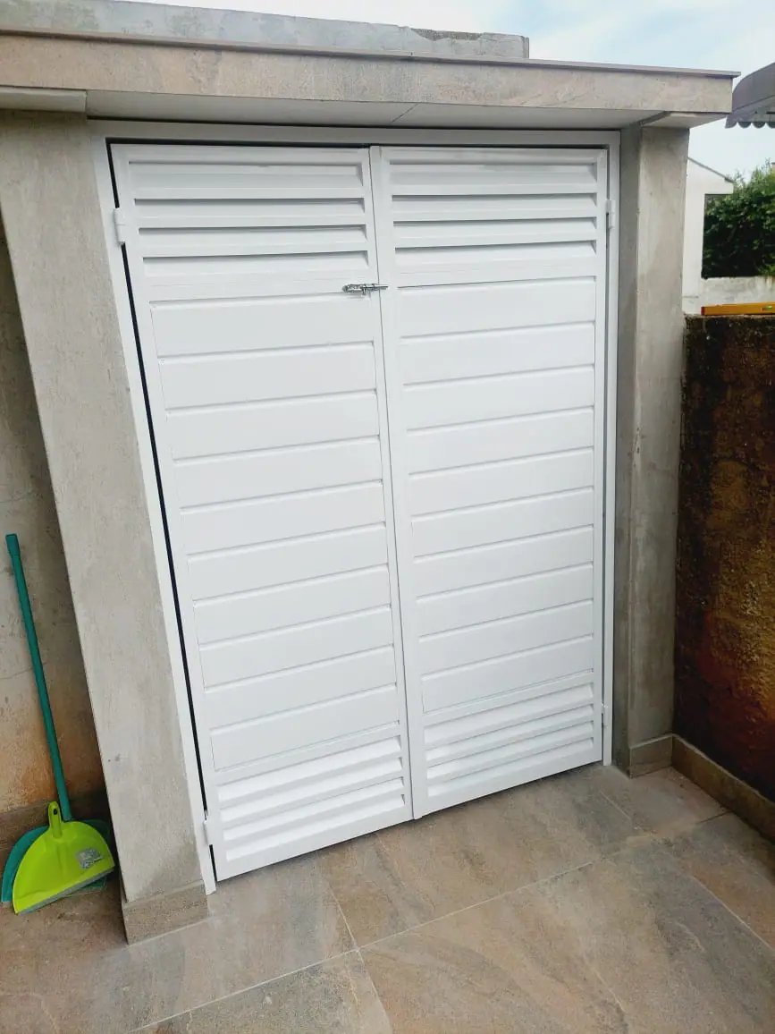 Porta de duas folhas em veneziana branca para abrigo
